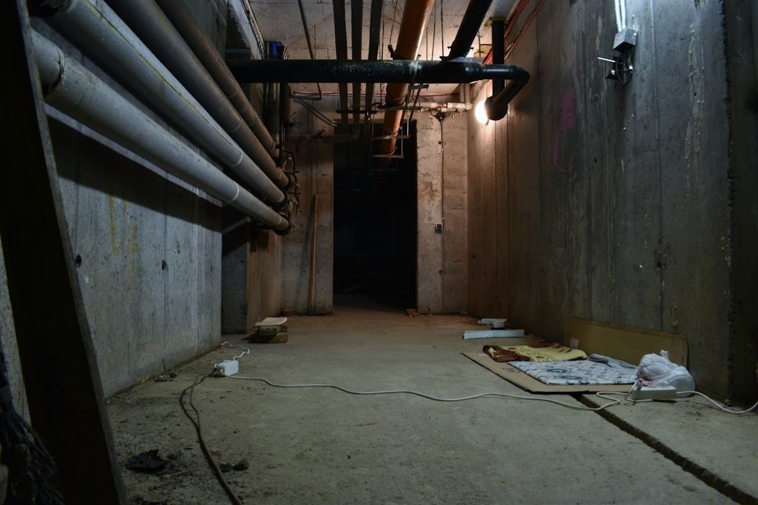 Rå kjeller med betongvegger, rørføringer og provisorisk gulvutstyr